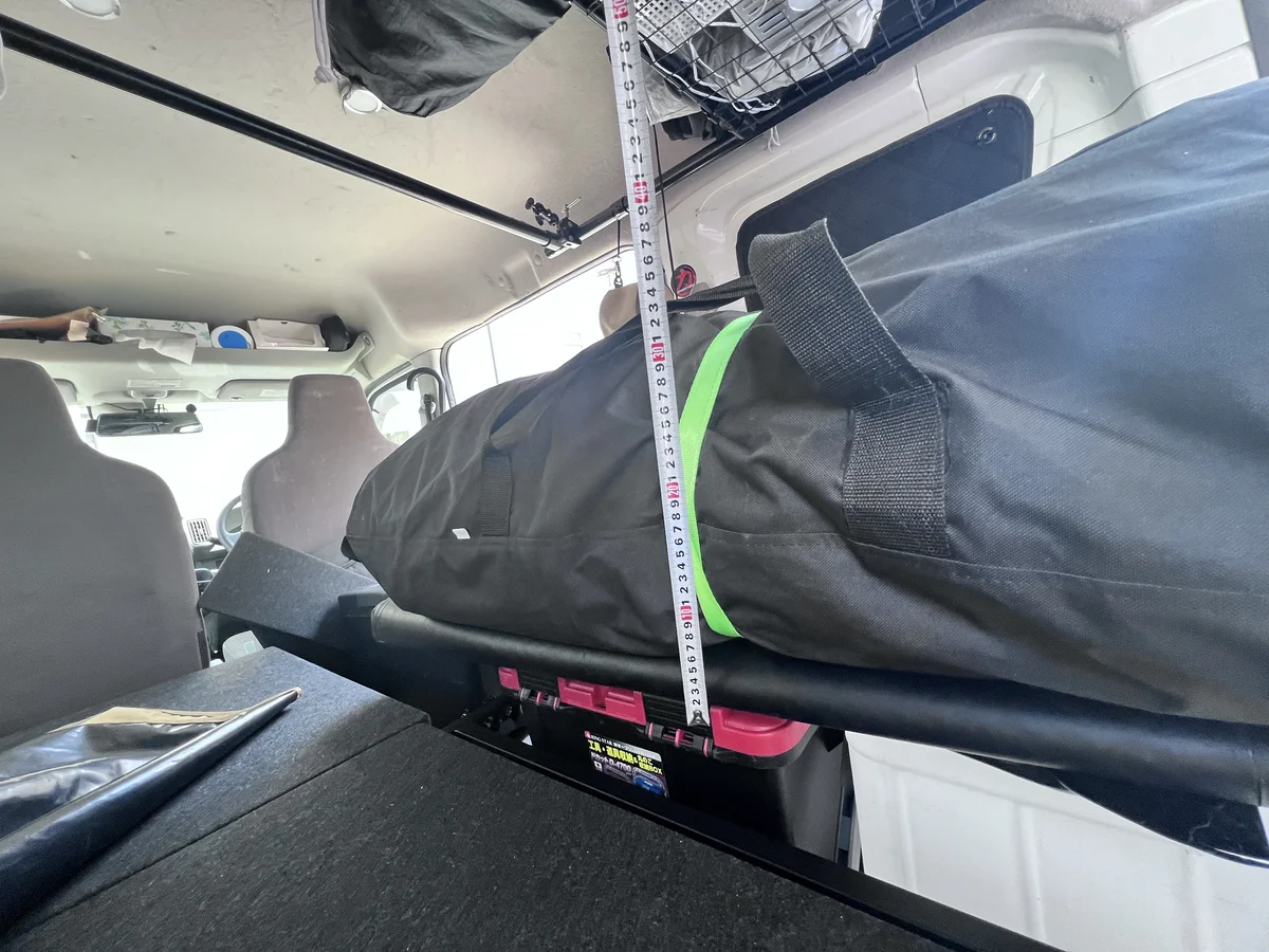 軽バン車内にゴムボートを積んだ状態で天井収納との高さやクリアランスを確認している様子